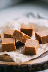 Fresh caramel fudge candies on a wooden plate with copy space in marble background