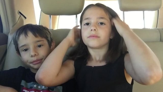  Aprende a pronunciar brother and sister playing imitate adults in the backseat of a car on a family trip