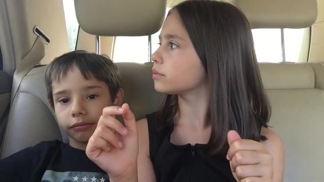   Aprende a pronunciar brother and sister playing imitate adults in the backseat of a car on a family trip