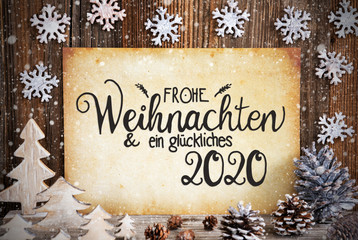 Fototapeta na wymiar Old Paper With German Text Frohe Weihnachten Und Ein Glueckliches 2020 Means Merry Christmas And Happy 2020. Christmas Decoration Like Tree, Fir Cone And Snow. Brown Wooden Background