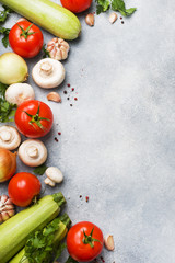 Set of different seasonal vegetables on a gray concrete background. Tomato zucchini onion garlic mushrooms parsley spices. Frame copy space.