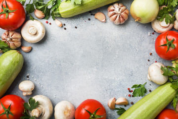 Set of different seasonal vegetables on a gray concrete background. Tomato zucchini onion garlic mushrooms parsley spices. Frame copy space.