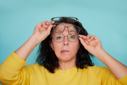 funny shocked face. frames trying eyeglasses. girl holding glasses standing on turquoise background, Concept: poor eyesight.