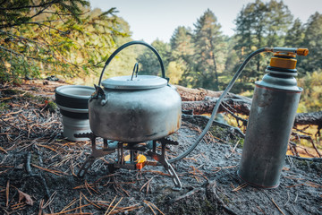 Gas burner, kettle and mug. Making tea in nature.