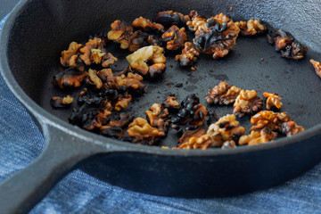 Walnuts cooked in a cast iron frying pan on a blue tea towel