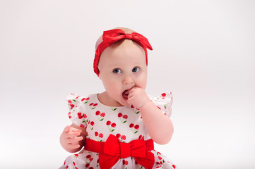 Little girl in white with a red dress with a bow on her head