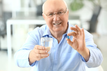 Elderly man taking medicine in office