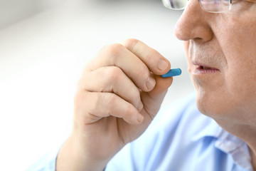 Elderly man taking medicine at home, closeup