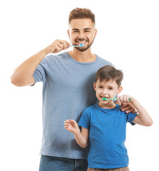 Portrait of father and his little son brushing teeth on white background
