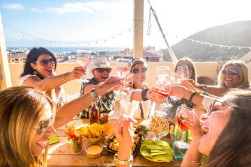 group of happy people mixed ages generations women having fun all together during celebration party - view of fiends clinking and toasting with red wine and table full of food