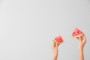 Female hands with pieces of juicy watermelon on light background