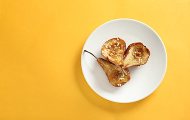 Plate with tasty cooked pears on color background