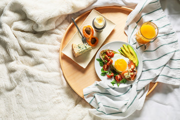 Tray with tasty breakfast on bed