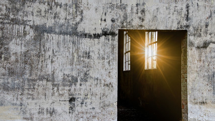 Lost places - concrete factory building, view through the door in the abandoned building, sun shines through the broken window