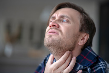 Blue-eyed man having awful pain in neck
