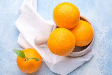 Bowl with fresh oranges on color background