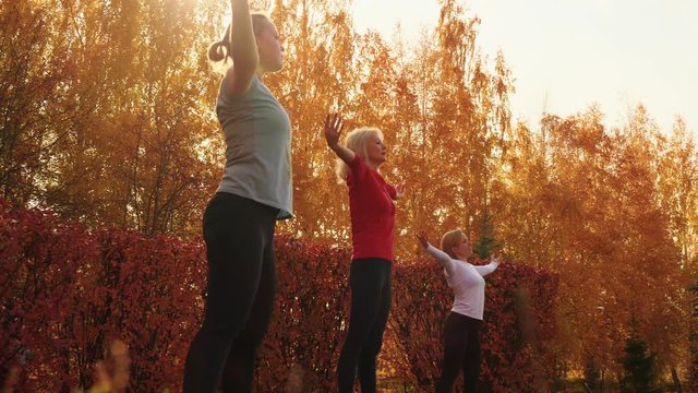 Beautiful sporty women training together in autumn park. Low angle view of attractive women in sportswear dancing together in autumn park