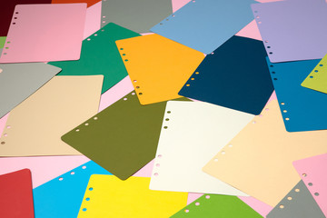 There are many different colored papers on the pink floor.