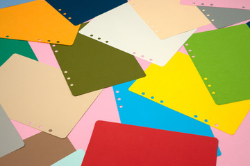 There are many different colored papers on the pink floor.