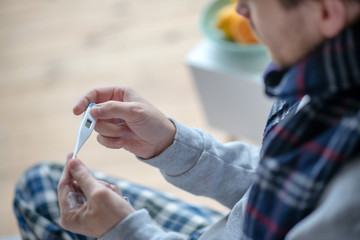 Close up of man using thermometer while feeling dizzy