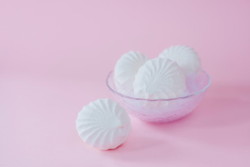 Delicious sweet marshmallows and cute little toy on pastel pink background