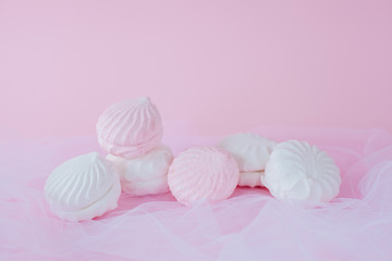 Delicious sweet marshmallows and cute little toy on pastel pink background