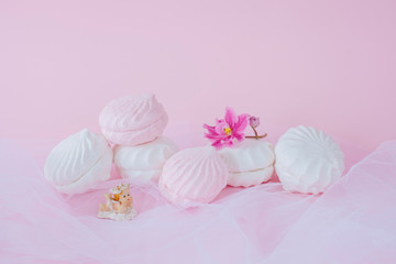 Delicious sweet marshmallows and cute little toy on pastel pink background