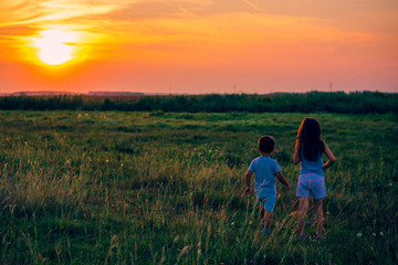 Brother and sister at sunset at field 