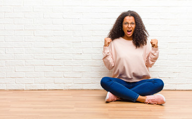 young african american black woman shouting aggressively with an angry expression or with fists...