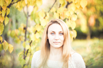 Blue eyed girl in autumn yellow leaves