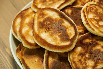 Stack of delicious homemade pancakes on plate, wooden table as background