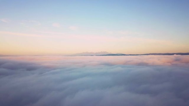 Aerial footage of beautiful morning landscape covered with low clouds. Morning view above clouds with High Tatras in distance.