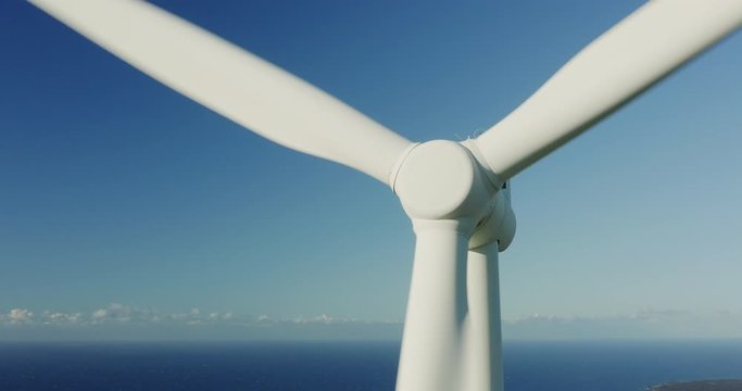 Aerial Close Up View Of The Center Of A Wind Turbine Spinning On A Sunny Day With Ocean And Sky In The Background, Clean Green Energy Future Concept