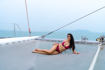 portrait sexy asian girl in bikini lay down relaxing on  cruise yacht with background of blue water...