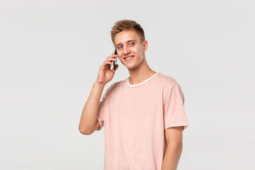 Pretty blond teenager in a pink t-shirt smiling speaking on the phone.