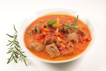 beef stew with tomato sauce and herbs on white background