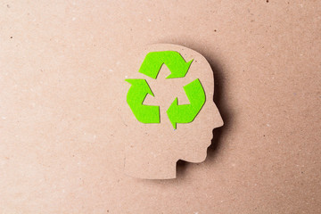 Head profile silhouette with recycle symbol on brown paper background.
