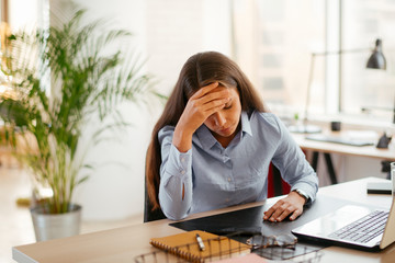 Young businesswoman in office having migraine