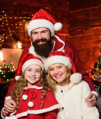 Fototapeta na wymiar Being best Santa for them. Father Santa claus costume with family celebrating christmas. Lovely daughter with parents wearing Santa hat. Love and kindness. Caring closest people. Togetherness concept