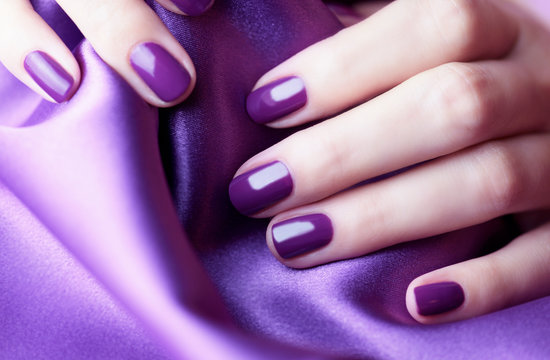 Female hand with purple nail. Purple nails on a purple background