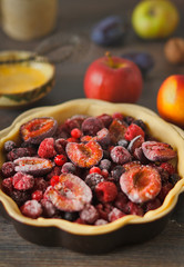 Homemade autumn red fruit pie, in a brown ceramic pie plate, ready to bake