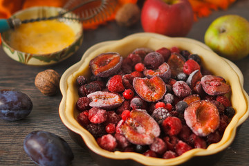 Homemade autumn red fruit pie, in a brown ceramic pie plate, ready to bake