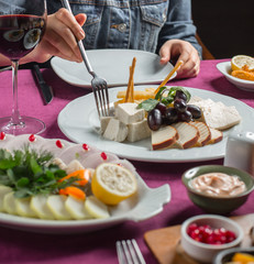 woman taking cheese from cheese plate with smoked, white, gouda, feta cheese, olive