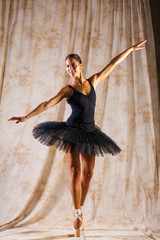 Full body portrait. Russian ballerina in a black dancing suit is posing in dark studio © Andrey_Arkusha