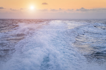 Fototapeta na wymiar Waves on the blue sea behind the speed boat water with bright of sunset