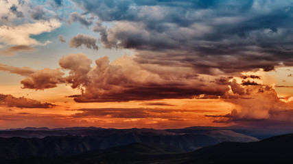 Dramatic light through the clouds against the backdrop of an exciting, vibrant stormy sky at sunset, dawn in the mountains. panorama, natural composition