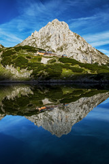 Sonnenspitze with coburger hut reflecting in the lake drachensee. Austria alps near leermos