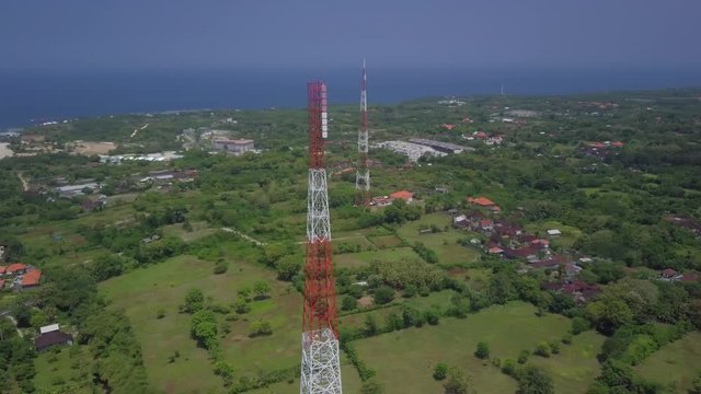 Network of two telecom tower masts close to each other. Cell phone or 4G 5G gsm cellular mobile network antenna mast on landscape. Spinning aerial drone view orbiting around