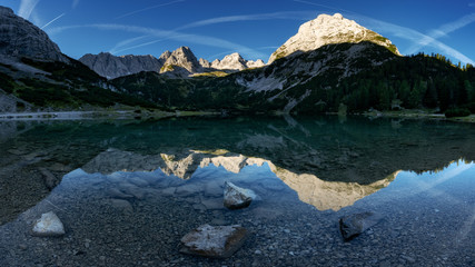 Seebensee reflection with Vorderer Drachenkopf mountain and coburger hut at sunrise