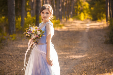 happy bride with a bouquet is walking the green park